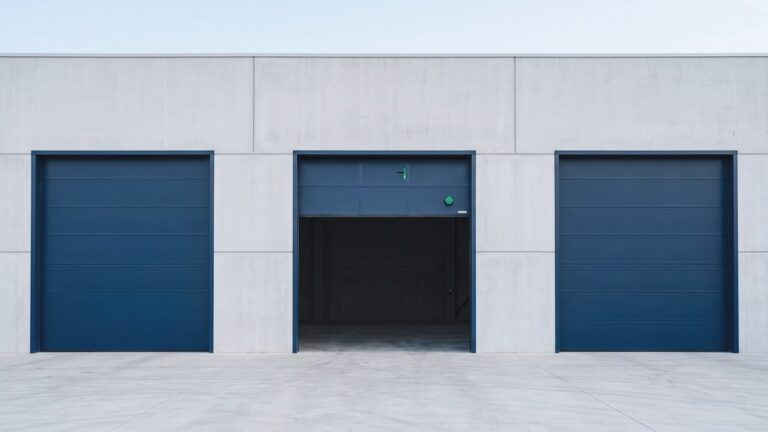 Tres puertas industriales idénticas en una fachada, con la central abierta